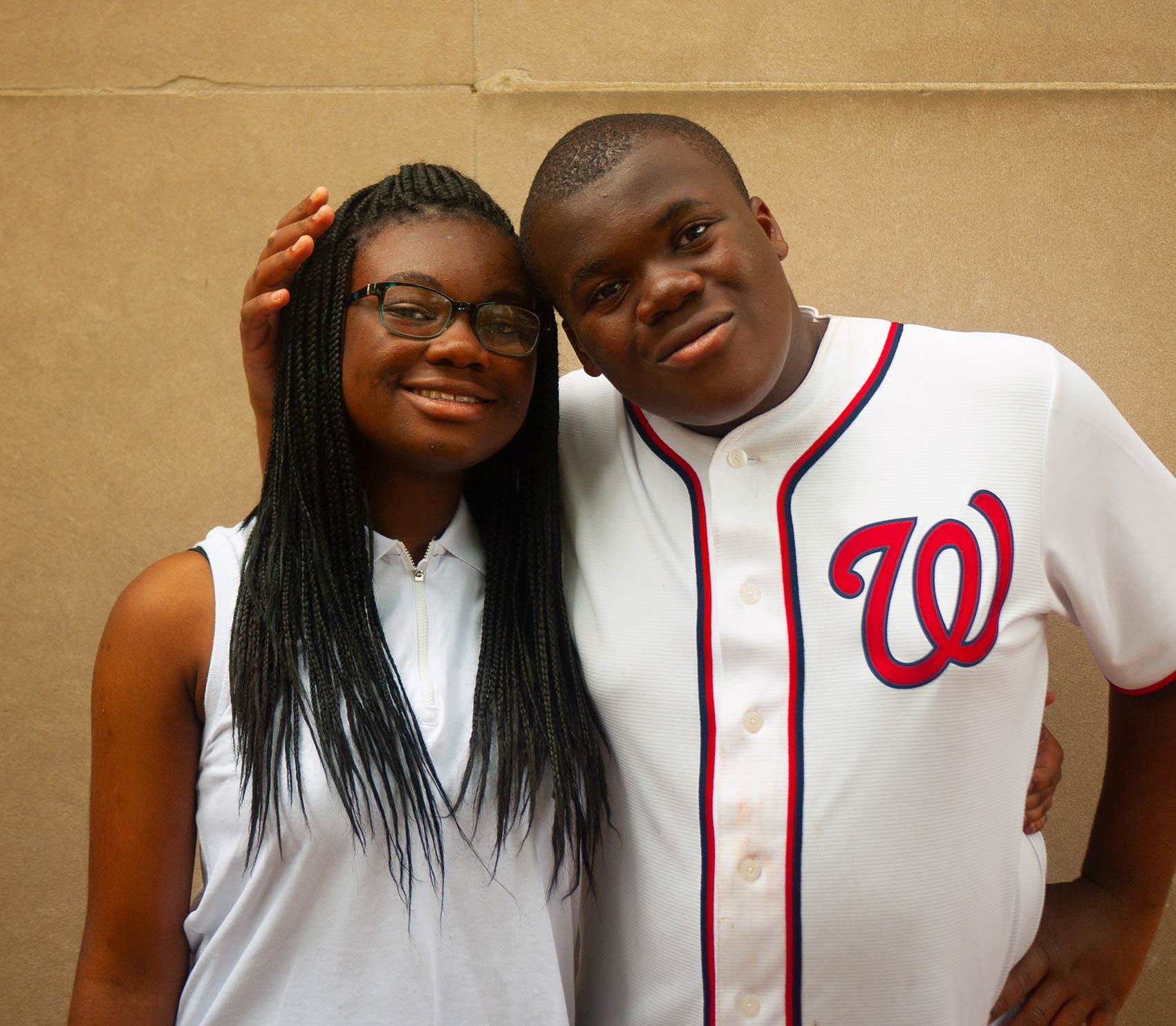 A brother and sister posing for the camera.