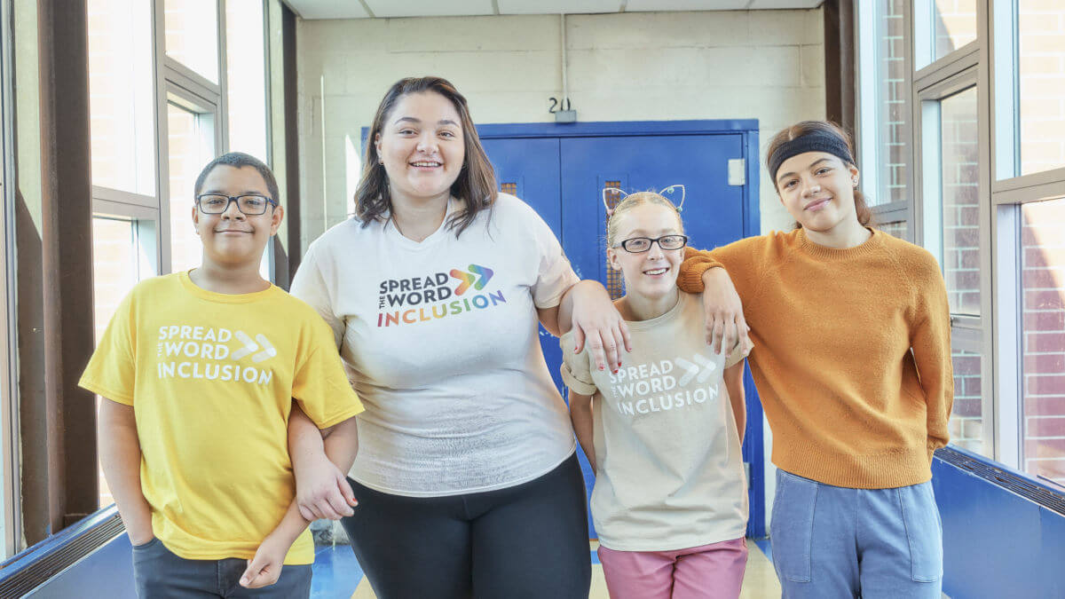 Group of students arm in arm in a school hallway.