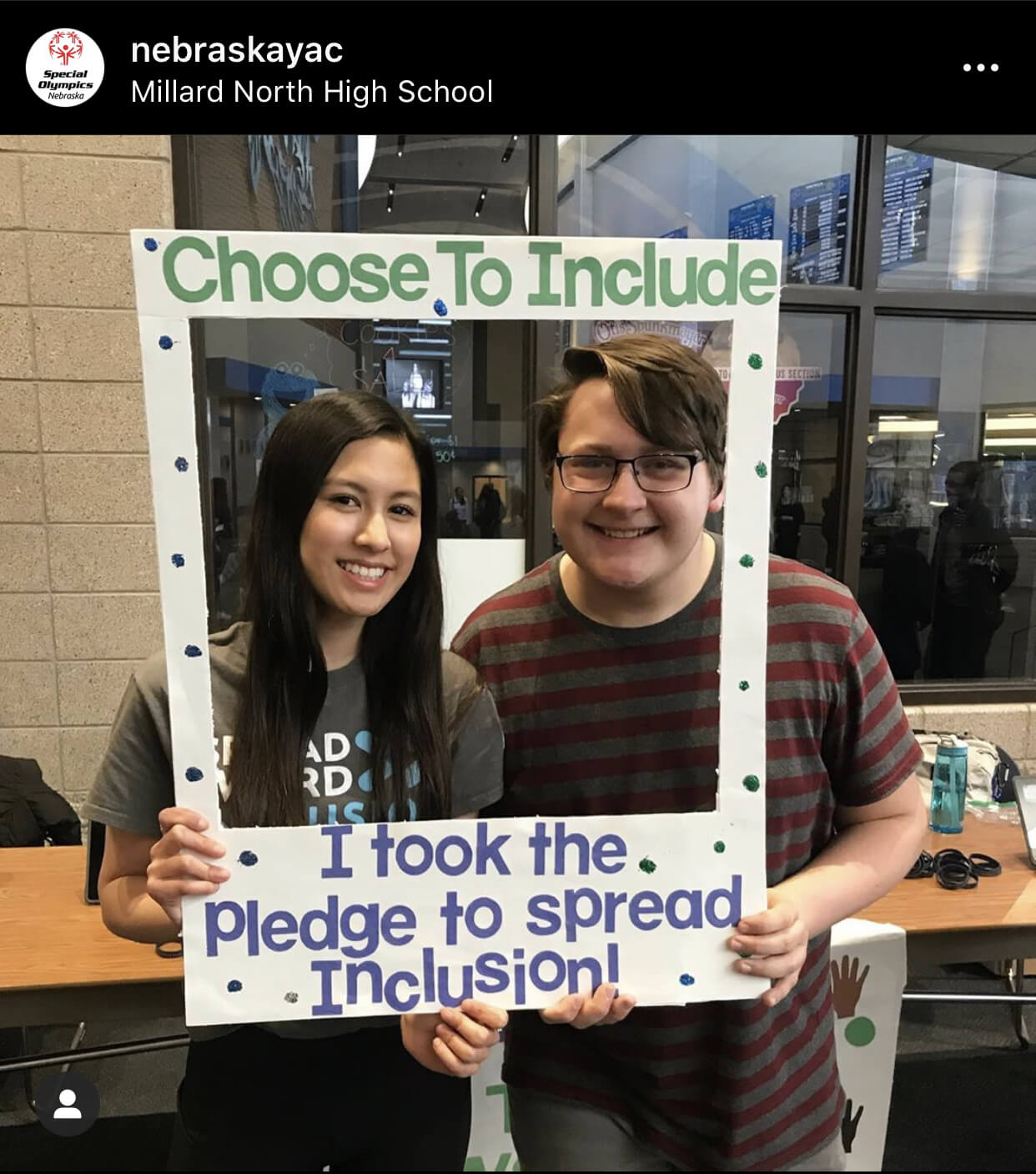 Two students standing inside of a photo frame that says “I took the pledge to spread inclusion”.