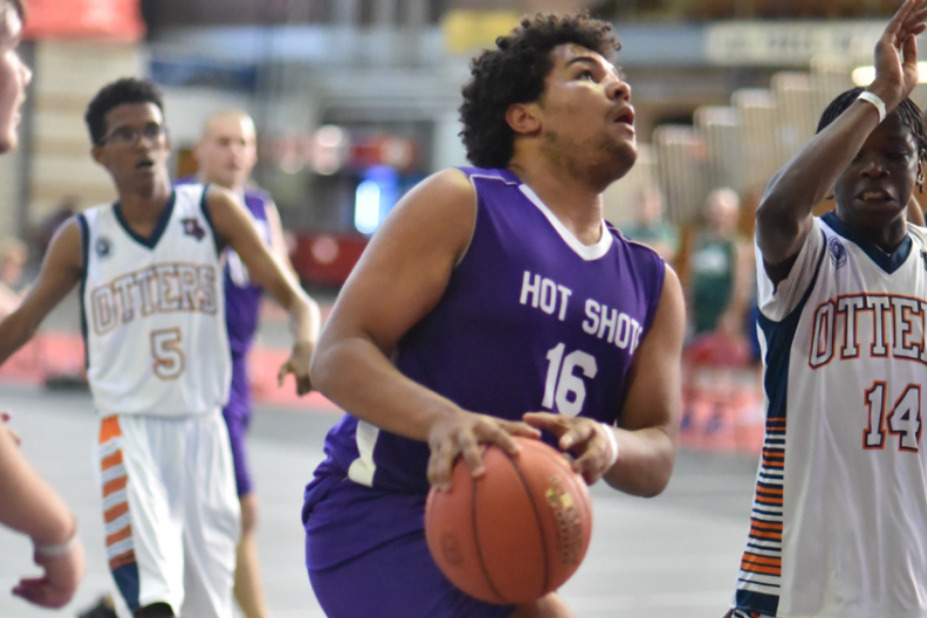 A Unified athlete going in for the basketball. He is wearing a purple jersey that says, 