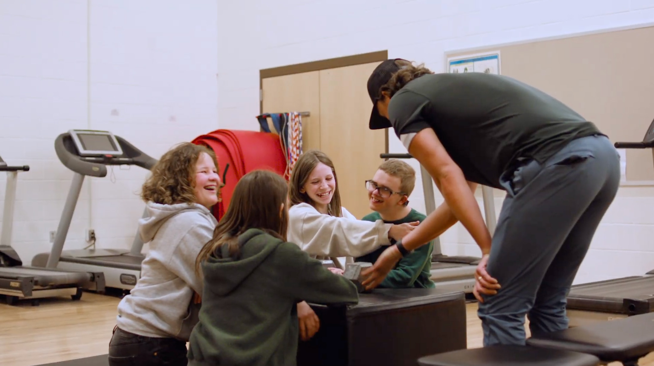 A group of young individuals participating in an activity together in a modern gym environment.